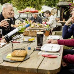 Group of friends eating seafood and having fun outside with musicians playing in the background at Johnnie Fox's pub, Dublin